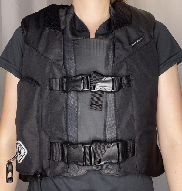 A person wearing a black vest with straps on it.