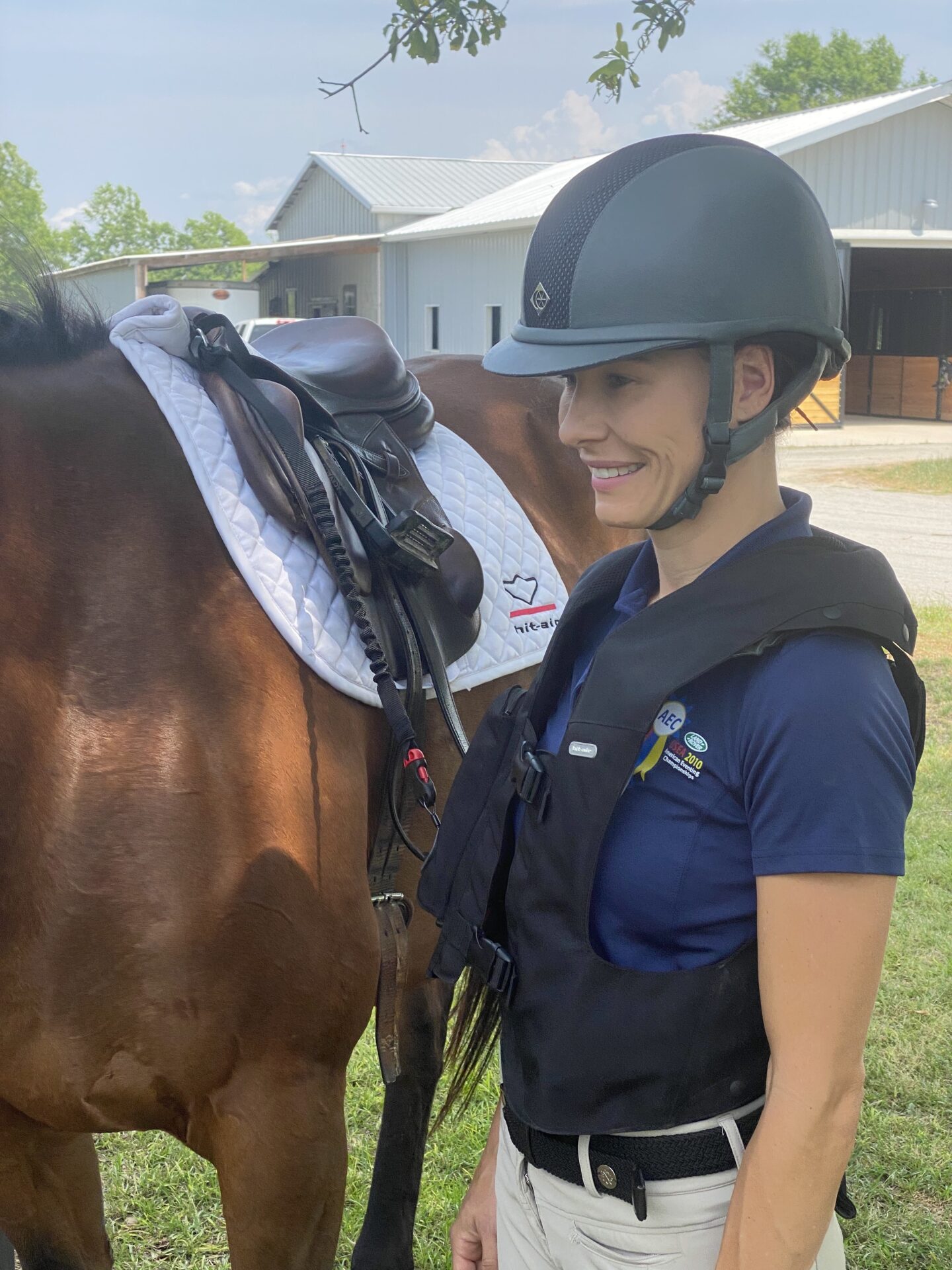 A woman in a helmet standing next to a horse.