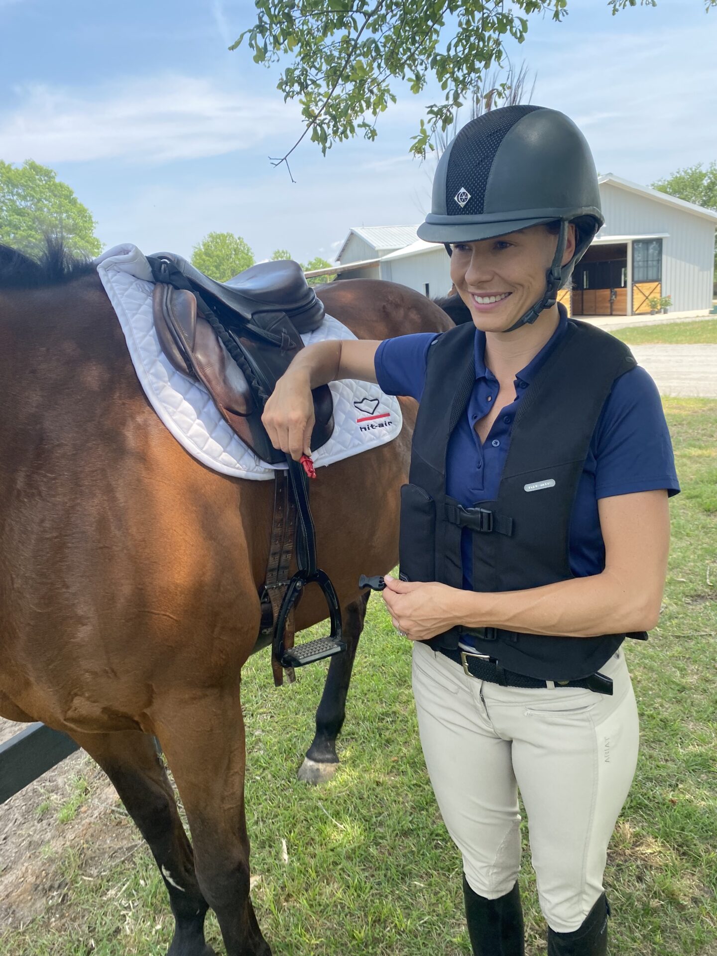 A woman in riding gear standing next to a horse.