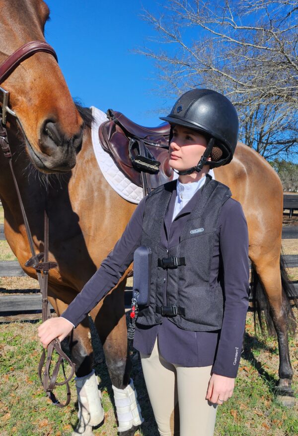 A woman in black jacket standing next to horse.
