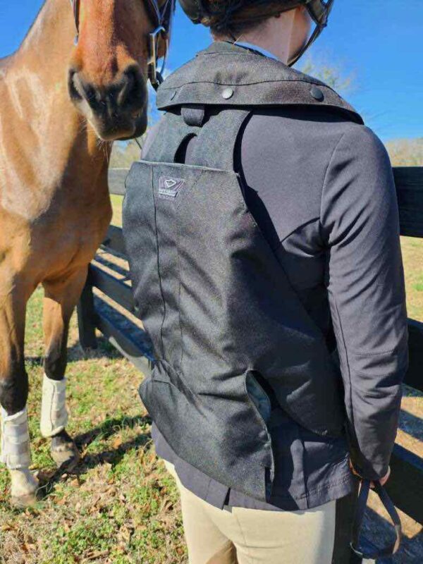 A person wearing a backpack and standing next to a horse.